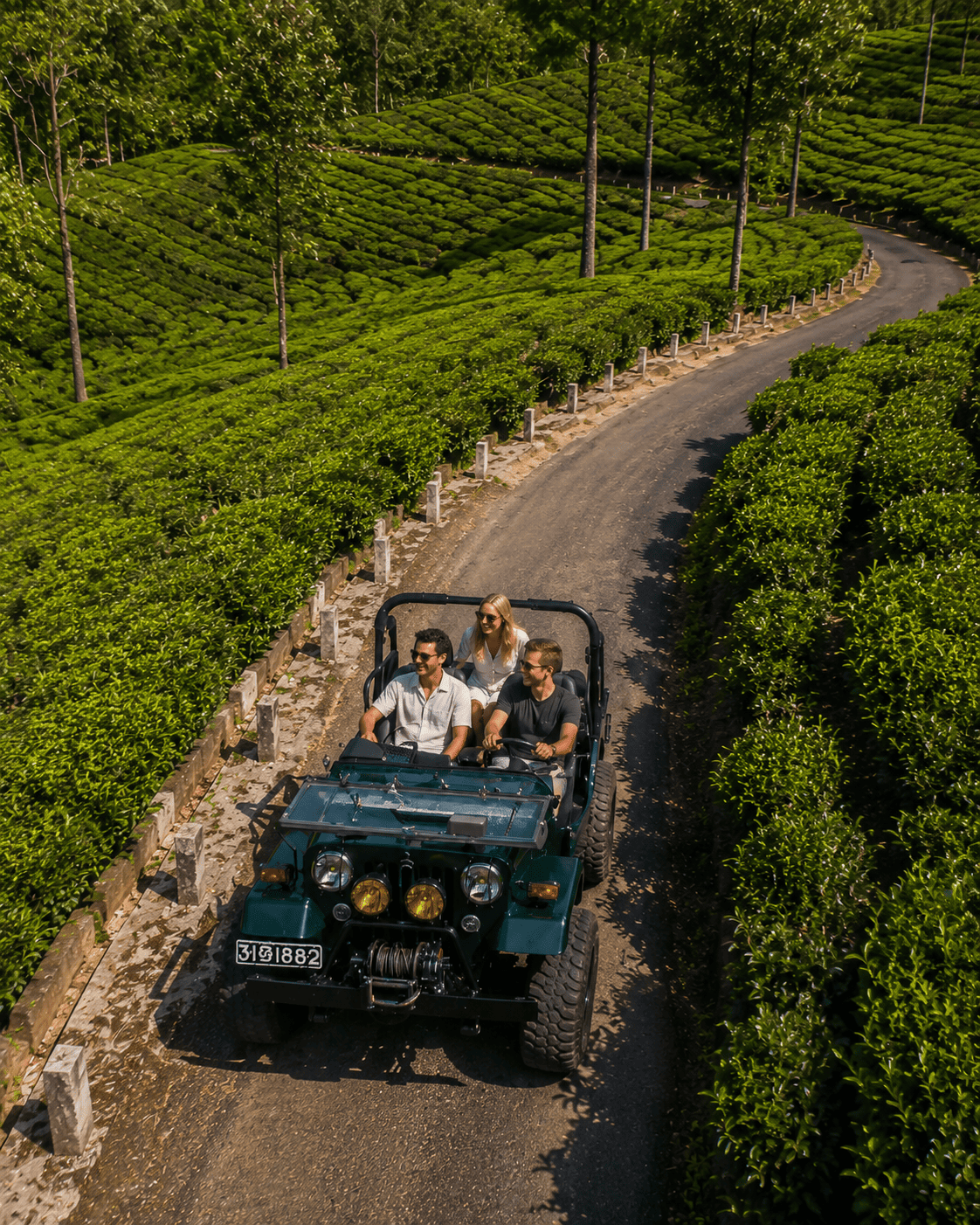A vintage green safari jeep driving through rolling tea plantations in Sri Lanka's emerald hinterland
